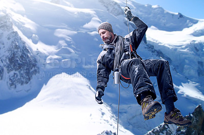 Buy stock photo Shot of a mountaineer hanging from a rope on a rockface