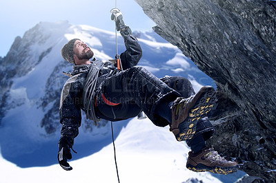 Buy stock photo Shot of a mountaineer hanging from a rope on a rockface