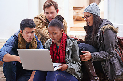 Buy stock photo Cropped shot of university students using a laptop while sitting on campus