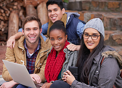 Buy stock photo Portrait of a group of college students using a laptop while sitting on campus