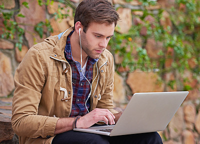 Buy stock photo Shot of a handsome male student using his laptop on campus
