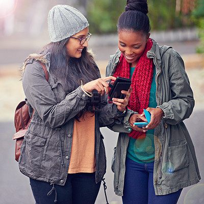 Buy stock photo Cropped shot of two girlfriends looking at a cellphone while on campus