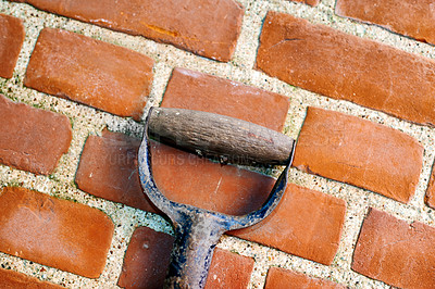 Buy stock photo Brick, wall and cement with handle of spade for gardening, outside and block with concrete for home build. Masonry, brickwork and weather for outdoor stone architecture, weathered and aged material