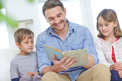 Buy stock photo Shot of a father reading a story to his son and daughter at home