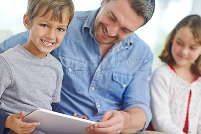 Buy stock photo Shot of a loving father using a digital tablet with his son and daughter at home