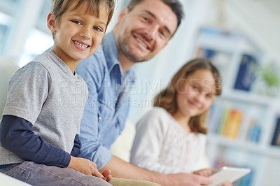 Buy stock photo Portrait of an adorable little boy sitting next to his sister and father while they use a digital tablet together 