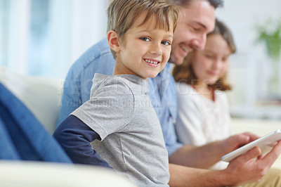 Buy stock photo Portrait of an adorable little boy sitting next to his sister and father while they use a digital tablet together 