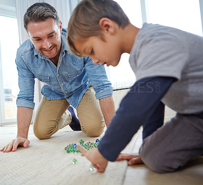 Buy stock photo Shot of a happy father and son playing marbles together at home