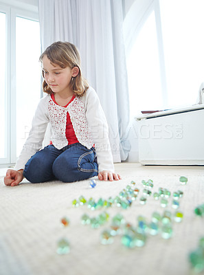 Buy stock photo Shot of an adorable little girl playing marbles at home