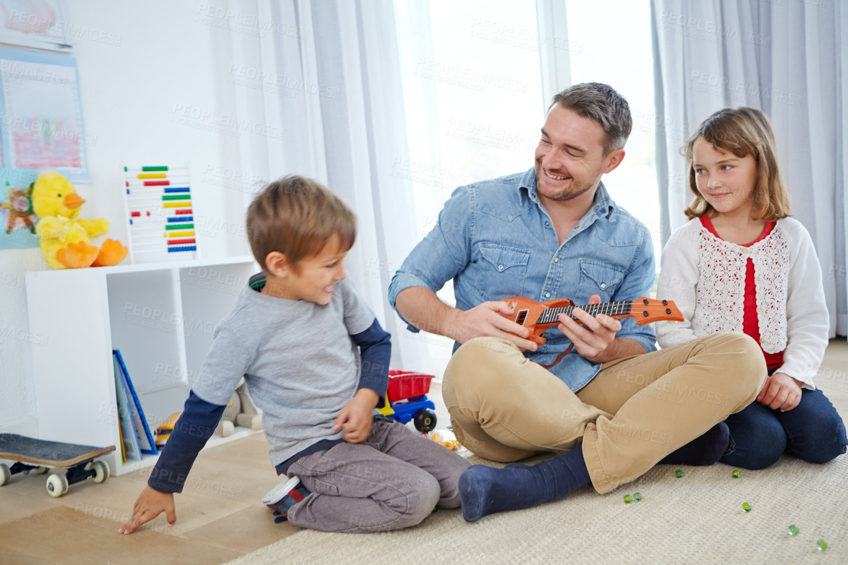 Buy stock photo Shot of a happy father playing the guitar for his son and daughter at home