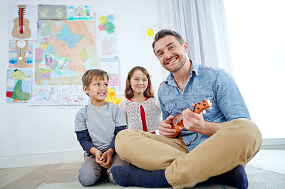 Buy stock photo Shot of a happy father playing the guitar for his son and daughter at home