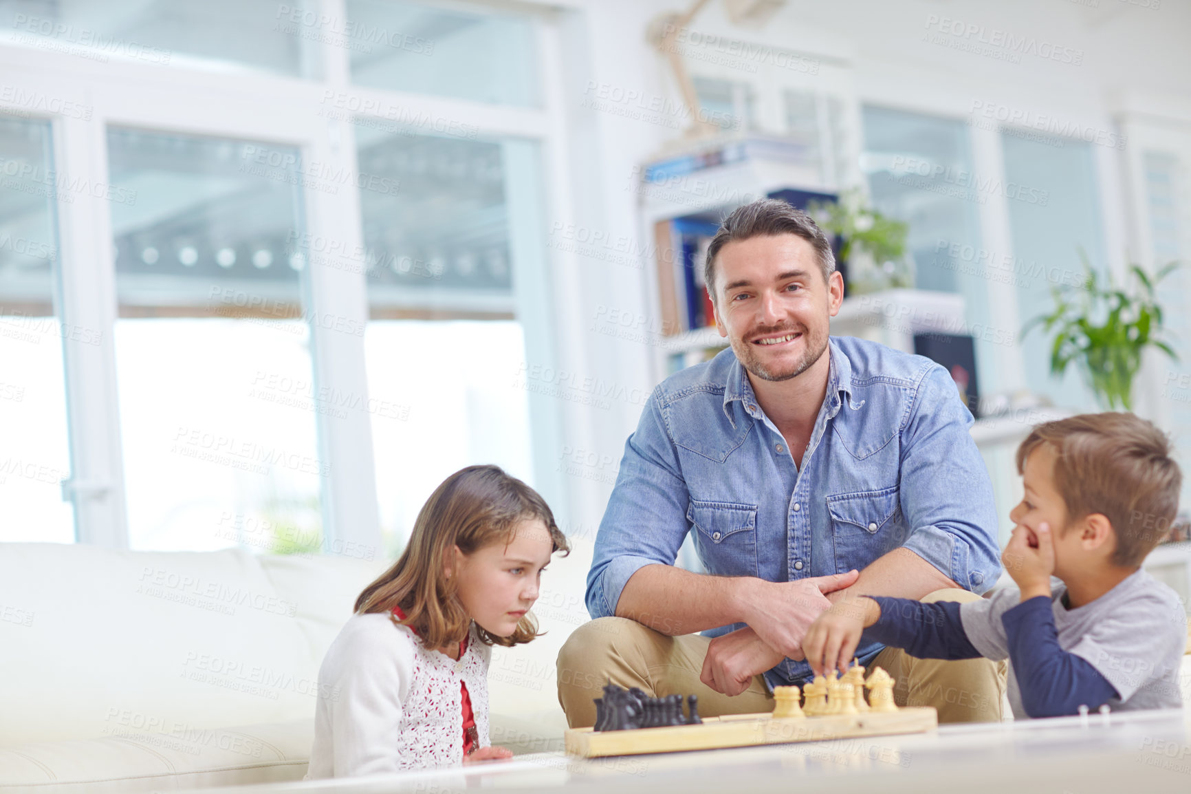 Buy stock photo Shot of a father playing a game of chess with his son and daughter at home