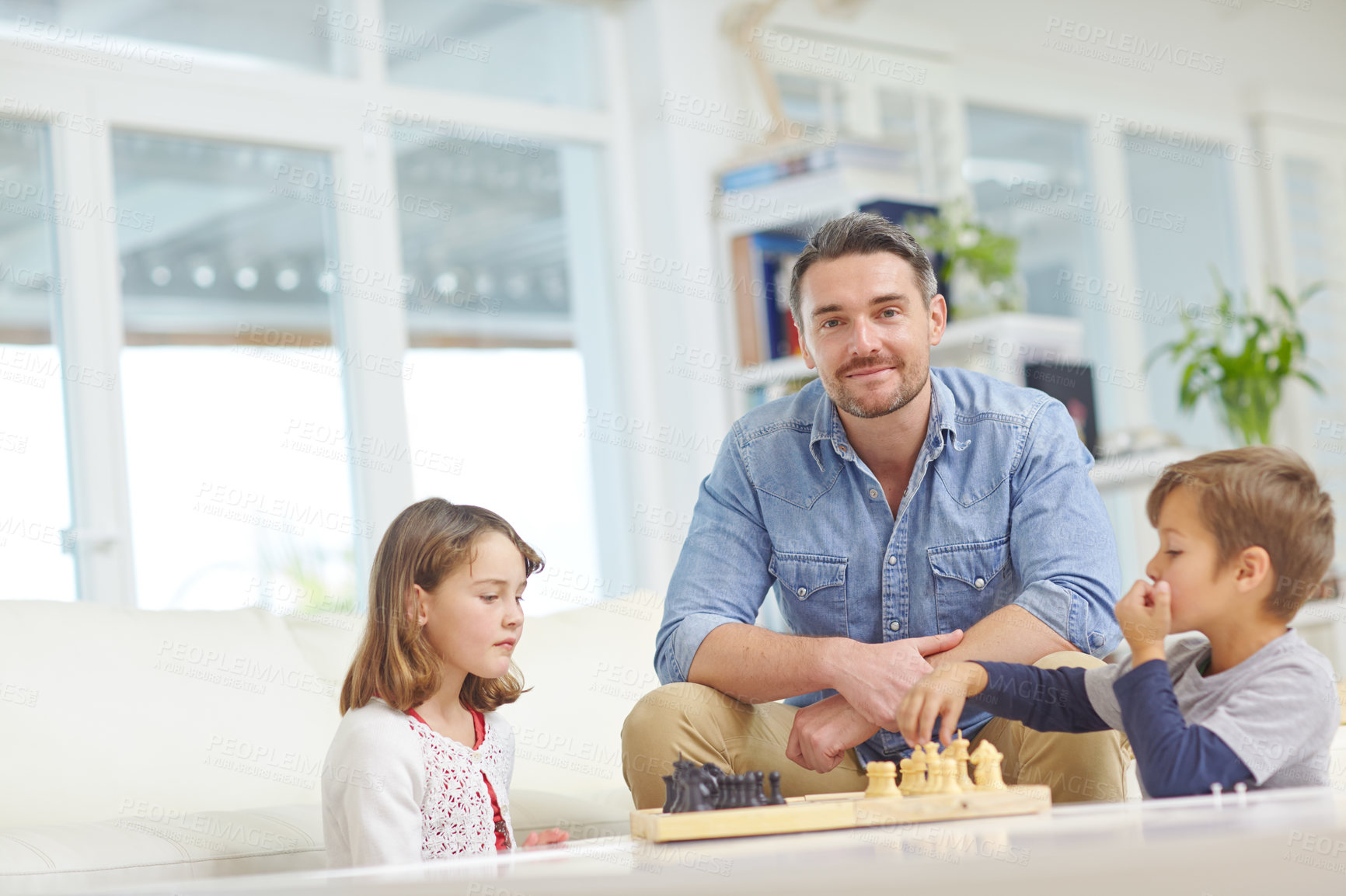 Buy stock photo Shot of a father playing a game of chess with his son and daughter at home