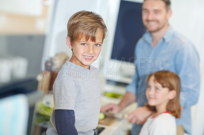 Buy stock photo Portrait of an adorable little boy standing in the kitchen with his father and sister