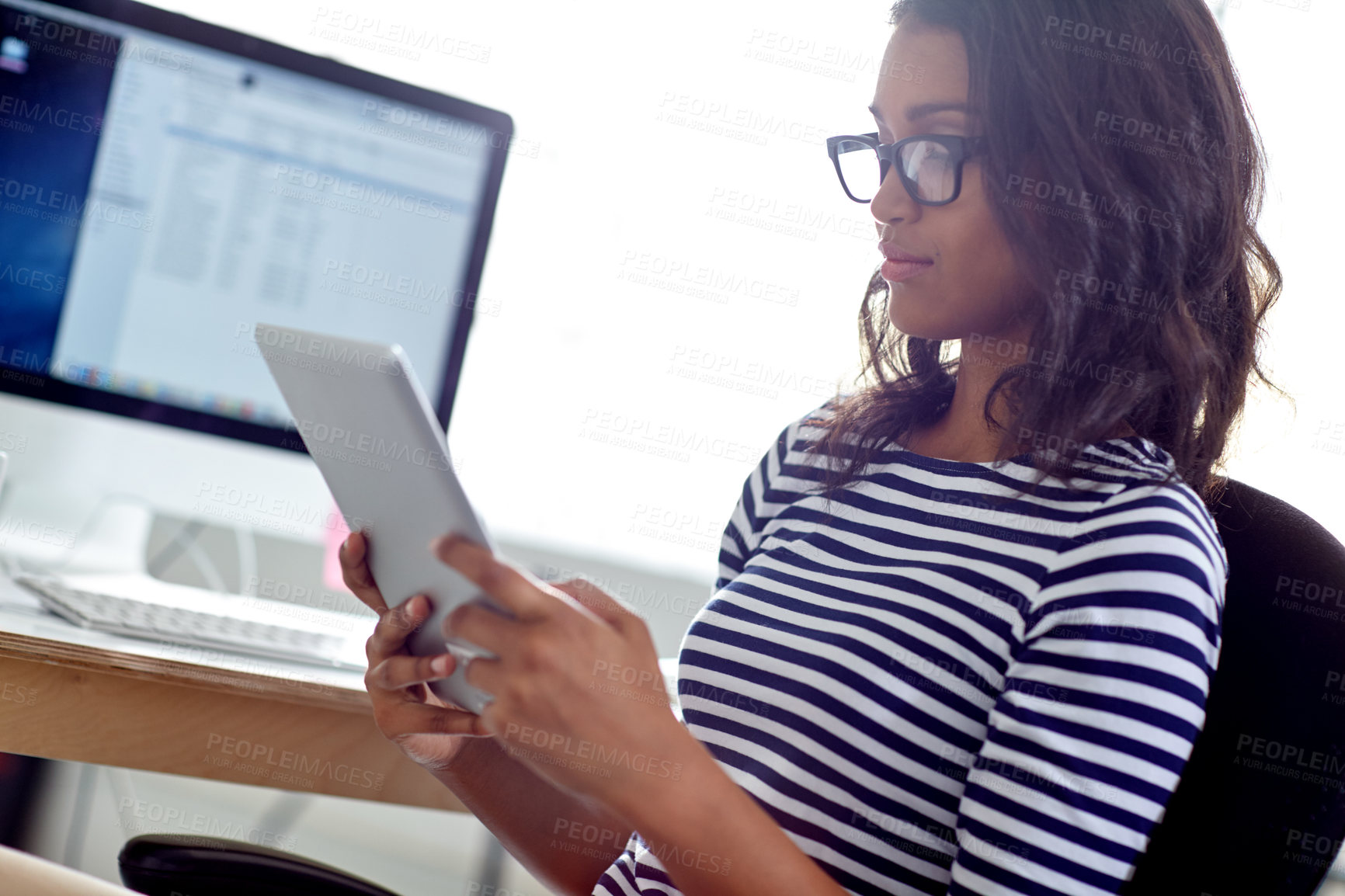 Buy stock photo Shot of a beautiful designer using her digital tablet at her desk