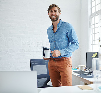 Buy stock photo Shot of a handsome designer holding a cup of coffee and a digital tablet