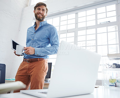 Buy stock photo Shot of a handsome designer holding a cup of coffee and a digital tablet