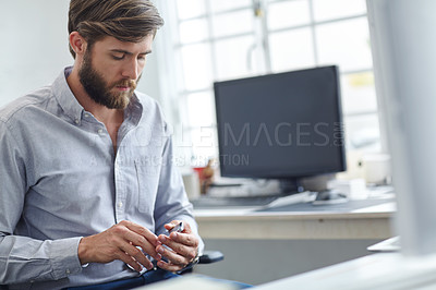 Buy stock photo Shot of a handsome designer looking seriously at his cell phone