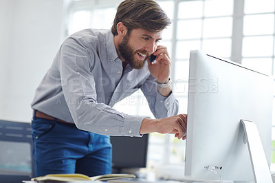 Buy stock photo Shot of a designer talking on his phone while reading something on his computer screen