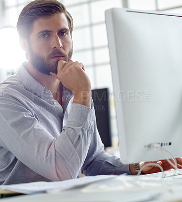 Buy stock photo Shot of a handsome designer sitting at his desk with his computer in front of him