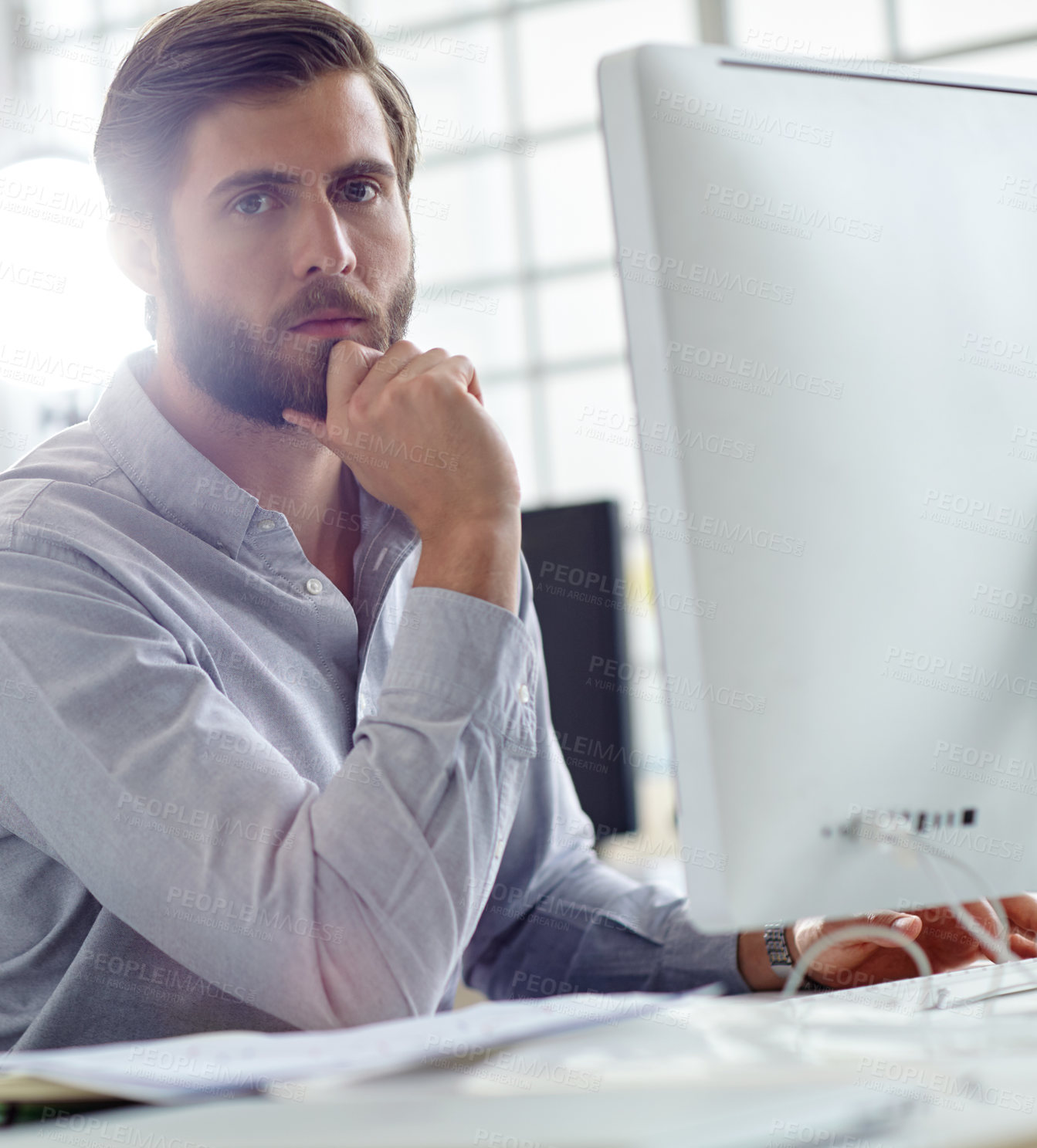 Buy stock photo Shot of a handsome designer sitting at his desk with his computer in front of him