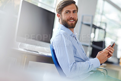 Buy stock photo Shot of a handsome designer at the office using his cellphone