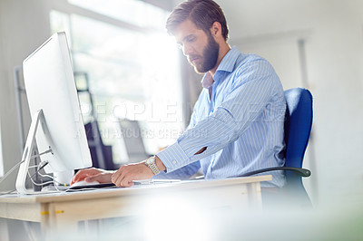Buy stock photo Shot of a handsome designer sitting at his desk with his computer in front of him