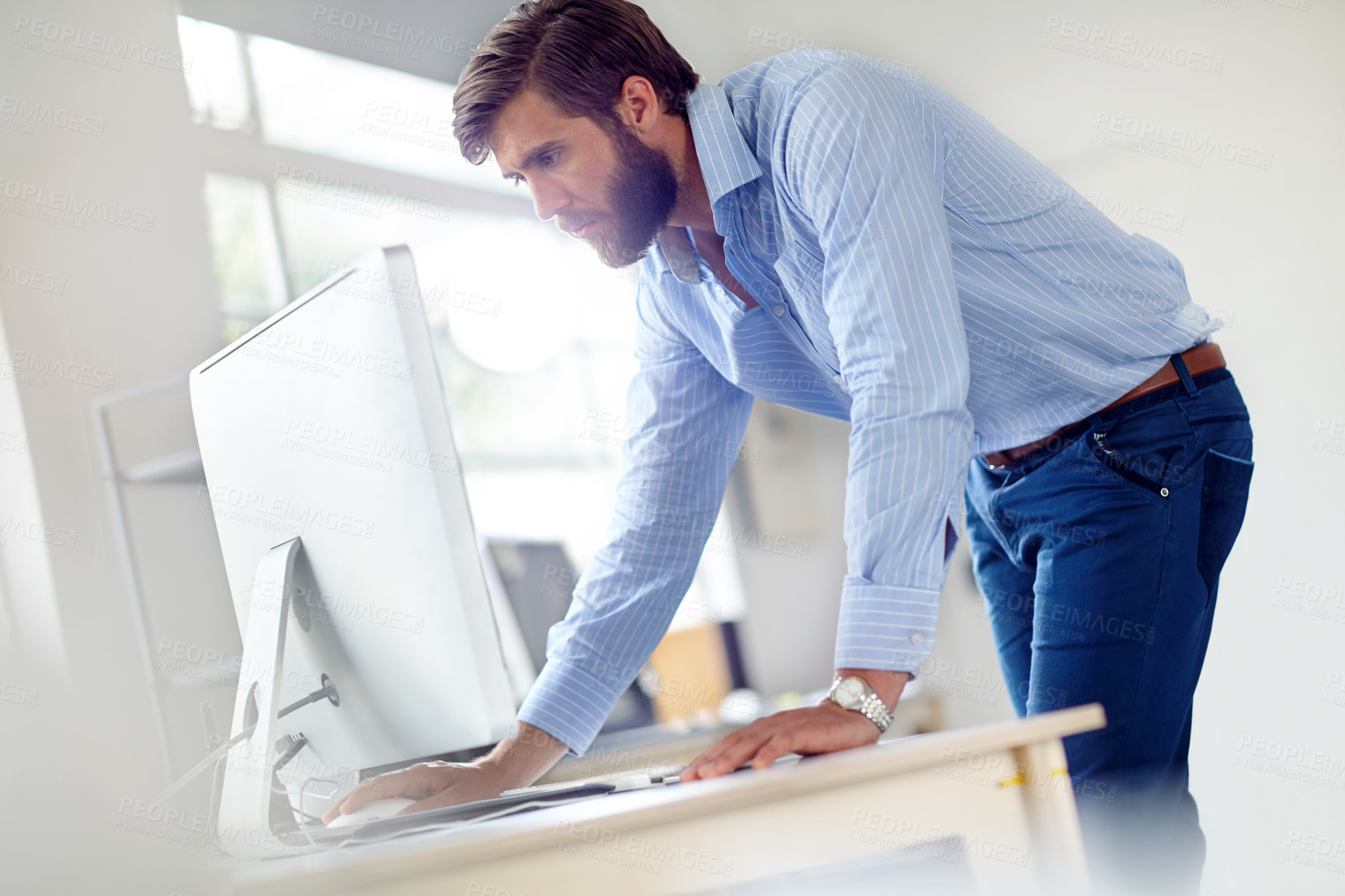 Buy stock photo Shot of a designer leaning towards his computer on his desk