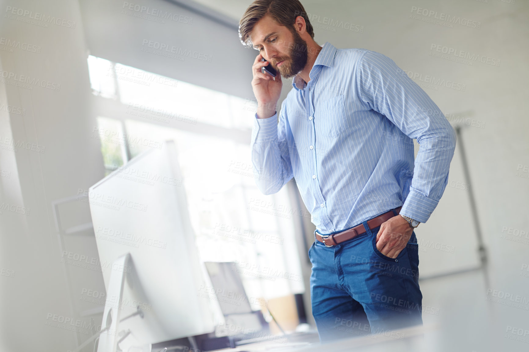 Buy stock photo Shot of a handsome designer talking on his phone at the office