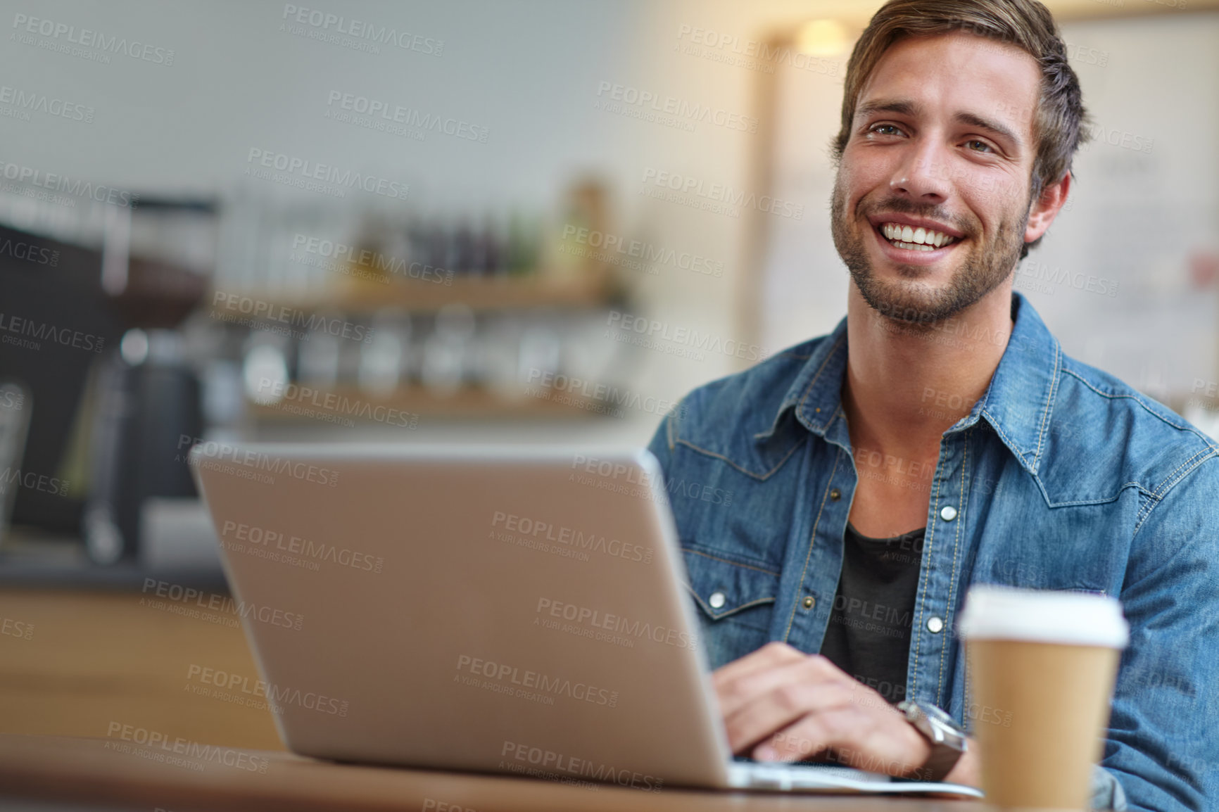 Buy stock photo Shot of a handsome young man using his laptop in a coffee shop