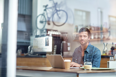 Buy stock photo Shot of a handsome young man sitting with his laptop in a coffee shop