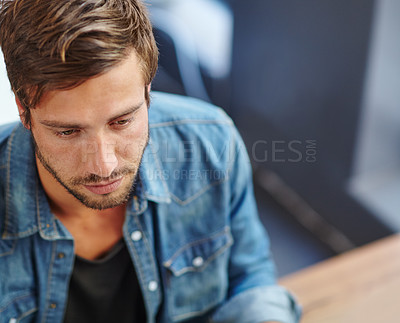 Buy stock photo High angle shot of a young man looking focussed while sitting at a restaurant table