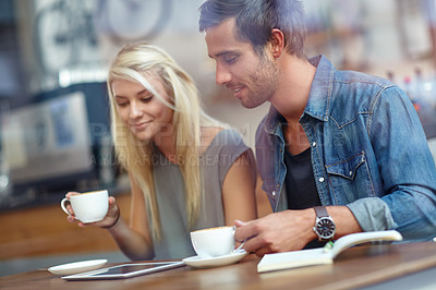 Buy stock photo Shot of a young couple using a tablet while on a coffee date