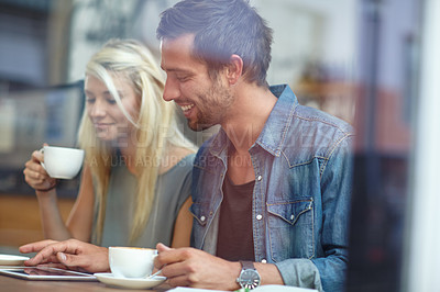 Buy stock photo Shot of a young couple using a tablet while on a coffee date