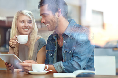 Buy stock photo Shot of a young couple sitting with a tablet while on a coffee date