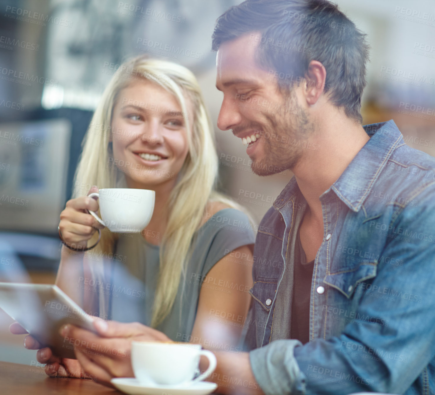 Buy stock photo Shot of a young couple sitting with a tablet while on a coffee date