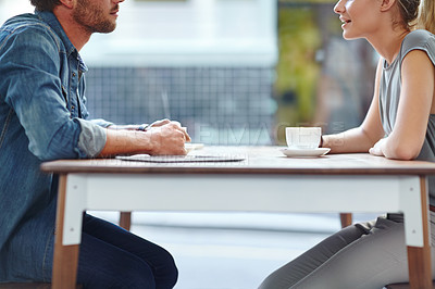 Buy stock photo Cropped side view of a young couple sitting opposite each other at a coffee shop
