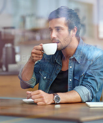 Buy stock photo Shot of a handsome young man drinking coffee at a cafe