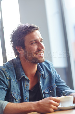 Buy stock photo Shot of a handsome young man looking thoughtful while drinking coffee at a cafe