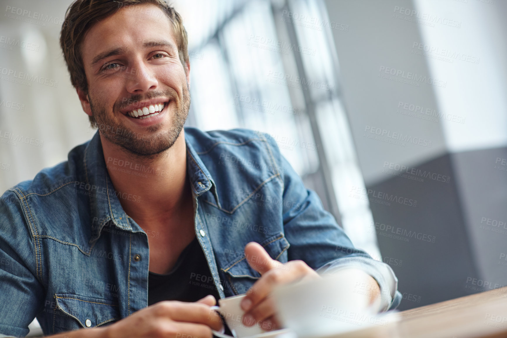 Buy stock photo Shot of a handsome young man having coffee at a cafe