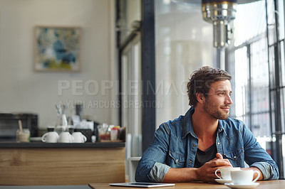 Buy stock photo Shot of a handsome young man looking thoughtful while having coffee at a cafe