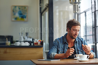 Buy stock photo Shot of a handsome young man having coffee at a cafe