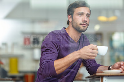 Buy stock photo Shot of a handsome young man looking thoughtful while drinking coffee at a cafe