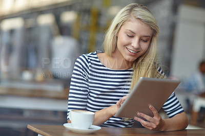 Buy stock photo Shot of a beautiful young woman using her tablet in a coffee shop