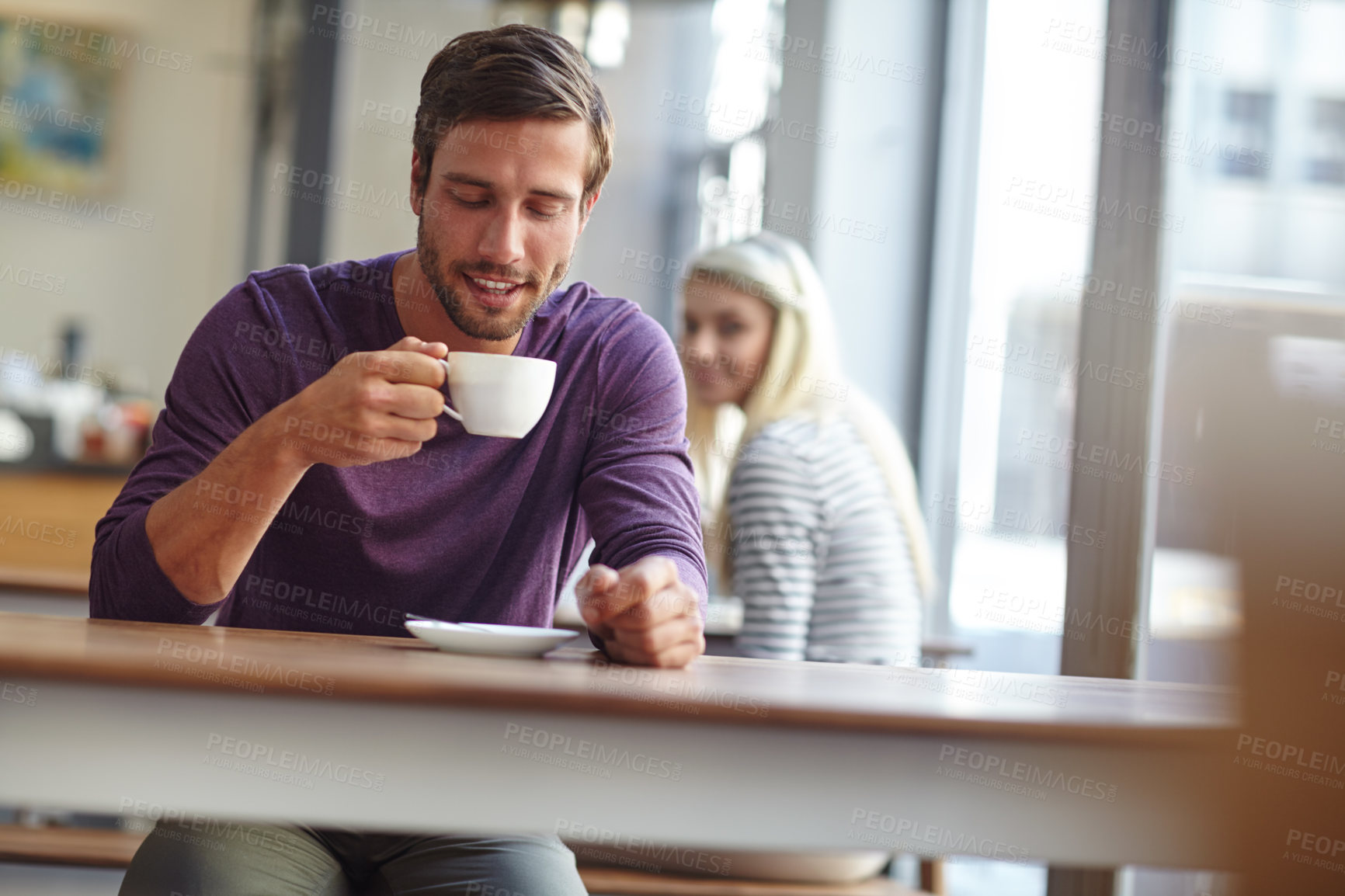 Buy stock photo Shot of a handsome young man drinking a cup of coffee at a cafe