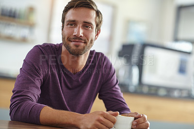 Buy stock photo Shot of a handsome young man enjoying a cup of coffee at a cafe
