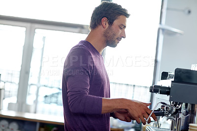 Buy stock photo Shot of a young male barista using an espresso machine in a coffee shop