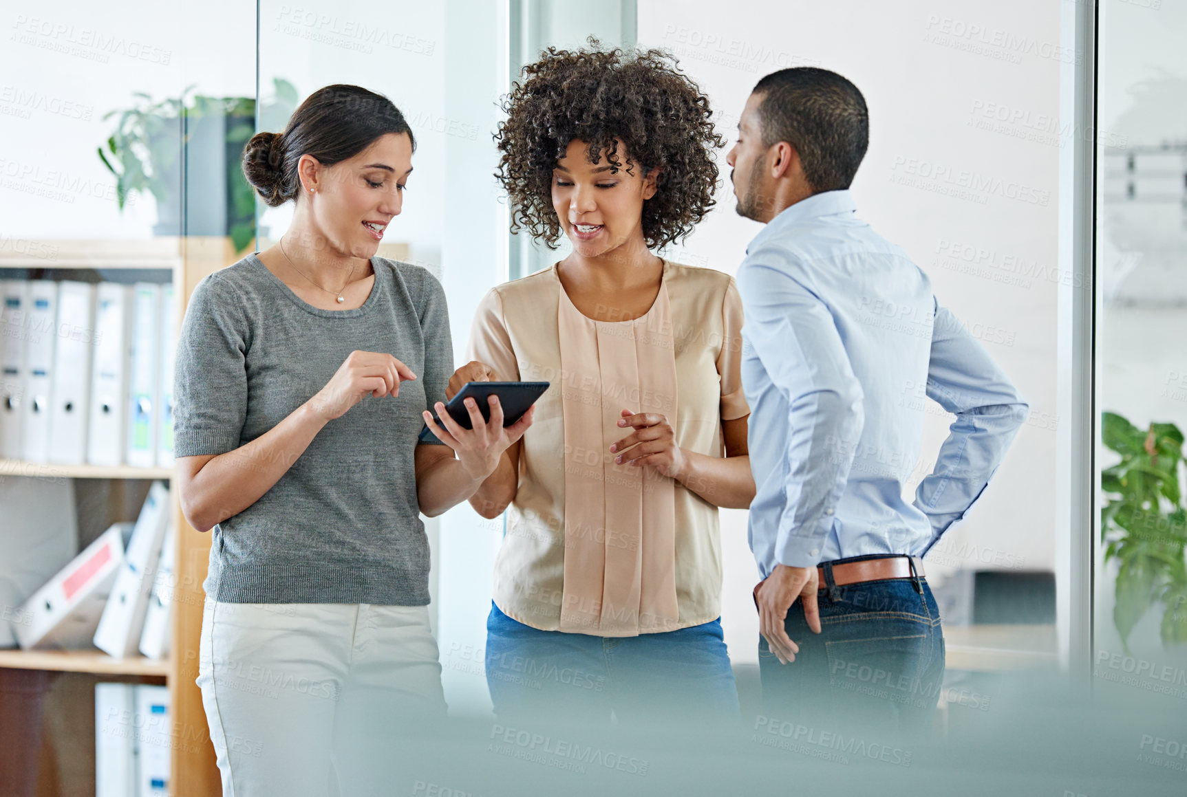 Buy stock photo Shot of office colleagues having a discussion over a digital tablet