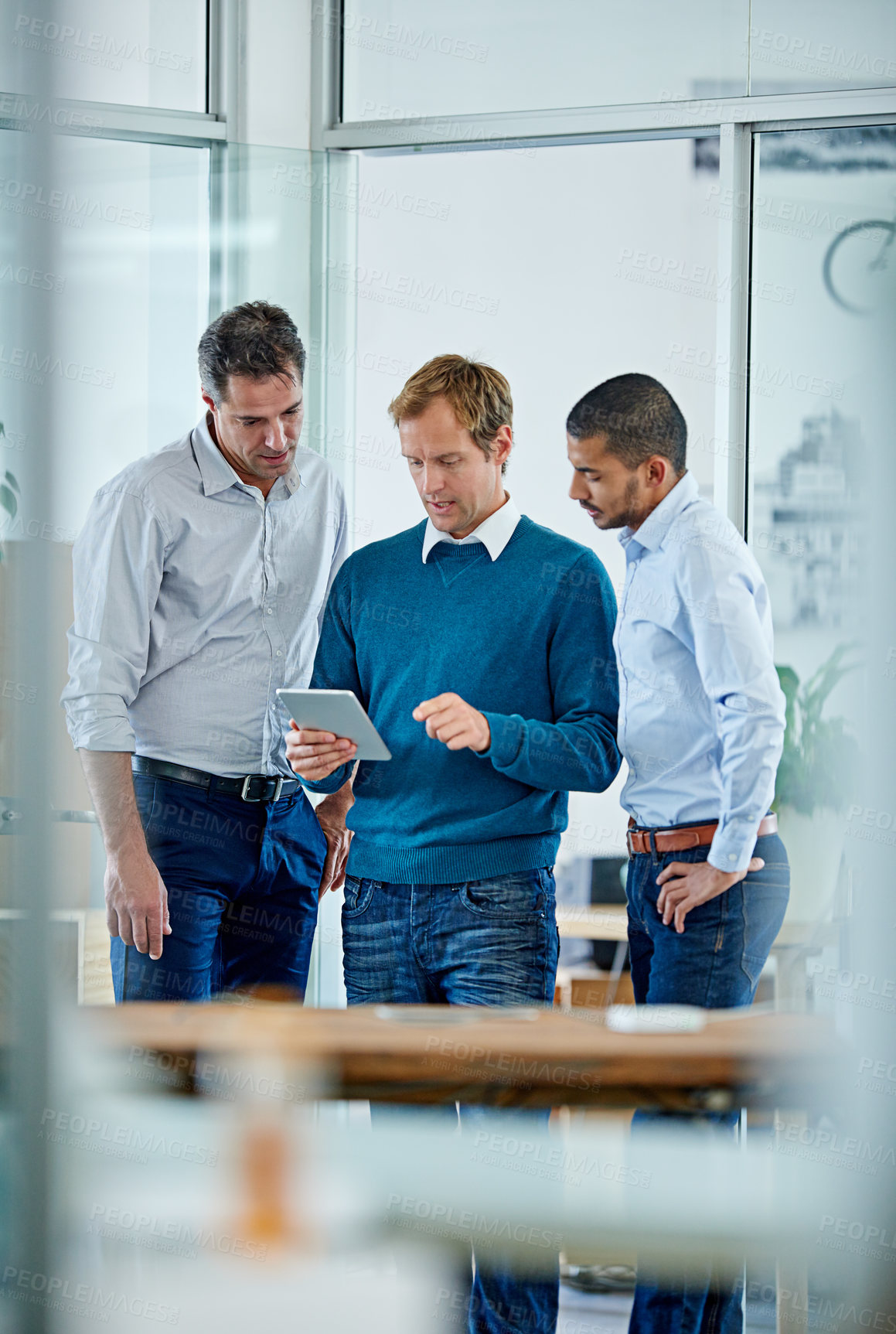 Buy stock photo Shot of a group of office colleagues having a discussion over a digital tablet