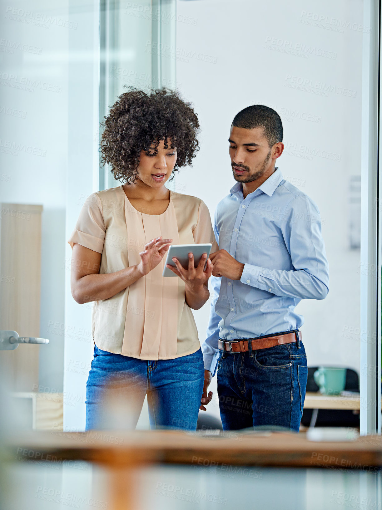 Buy stock photo Shot of two office colleagues having a discussion over a digital tablet